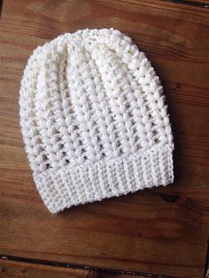 a white knitted hat sitting on top of a wooden table