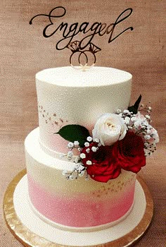 there is a wedding cake with flowers on the top and an engaged sign above it