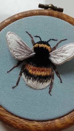 a close up of a bee on a piece of cloth in a wooden hoop frame