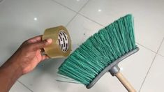 a hand holding a green brush on top of a tile floor