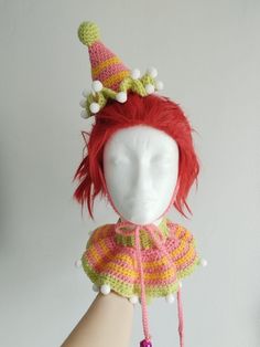 a doll with red hair wearing a pink and green hat on it's head