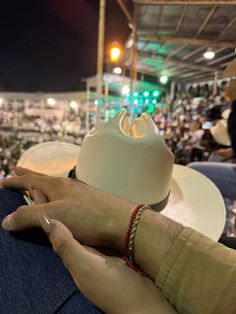 a person's hand holding a cell phone in front of a crowd