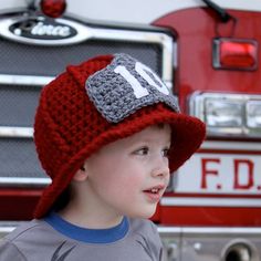 a young boy wearing a red hat standing in front of a fire truck