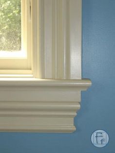 the corner of a room with blue walls and white molding on the window sill