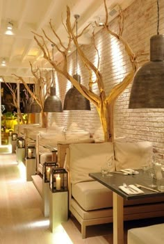 the interior of a restaurant with white couches and wooden tables in front of a brick wall