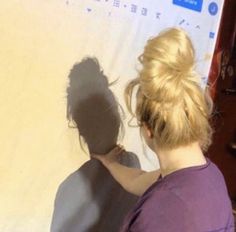 a woman is painting the wall with her shadow