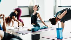 a group of women doing yoga poses in a room with their hands on the ground