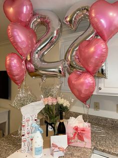 pink and silver balloons in the shape of numbers are displayed on a kitchen countertop