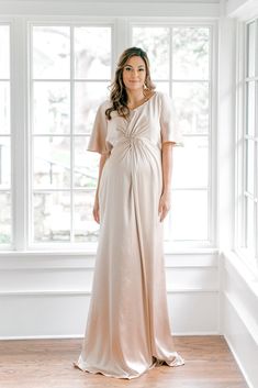 a woman standing in front of a window wearing a dress