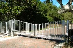 a white gate is open on a brick walkway