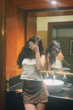 a woman standing in front of a bathroom mirror with her hands on her head while looking at herself in the mirror