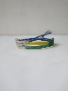 two bracelets with different colors and designs on them sitting on a white table top