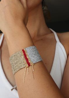 a woman is talking on her cell phone while wearing a silver bracelet with red beads