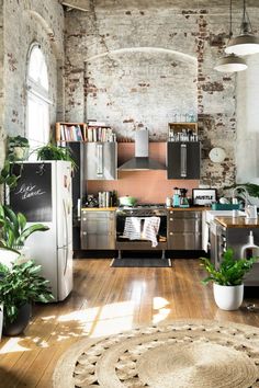 an industrial style kitchen with brick walls and wooden flooring, potted plants on the counter