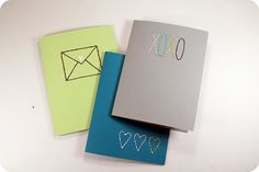 three notebooks with different designs on them and one has an envelope in the middle