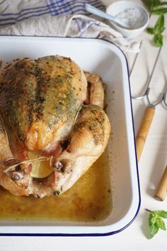 a roasted chicken in a baking dish with garlic and parsley