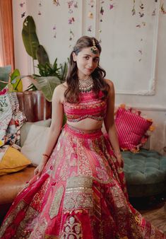 a woman in a red and gold bridal gown standing next to a green couch