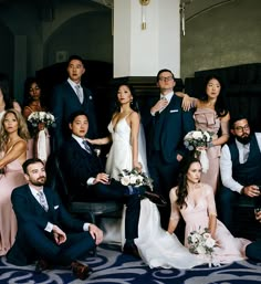 a group of people in formal wear posing for a wedding photo with the bride and groom