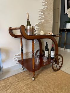 a wooden cart with wine bottles and glasses on it