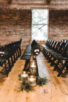 a long wooden table with candles and flowers on it in front of a brick wall