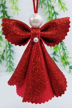 a red angel ornament hanging from a christmas tree