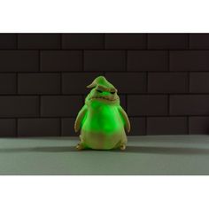 a green toy sitting in front of a brick wall