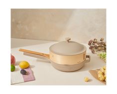 a pan with wooden handle sitting on top of a table next to fruit and vegetables