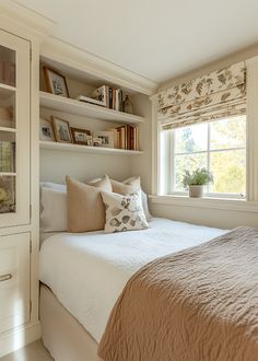 a bed sitting under a window next to a book shelf