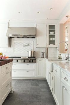 a large kitchen with white cabinets and marble counter tops, along with stainless steel appliances