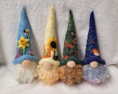 four gnomes are lined up in the same row on a white surface, one has blonde hair and two have blue eyes