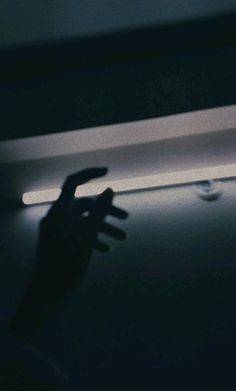 a person reaching for something in the dark with their hand and arm extended out to touch it