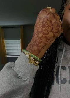 a woman with braids and tattoos on her arm is holding up her hand to the camera