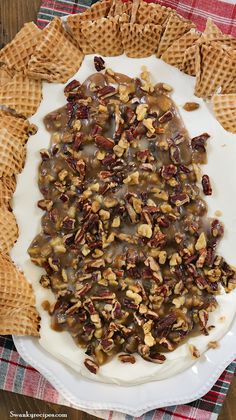 a white plate topped with waffles covered in chocolate and pecans on top of a checkered table cloth