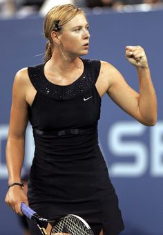 a woman holding a tennis racquet in her right hand and fist raised up