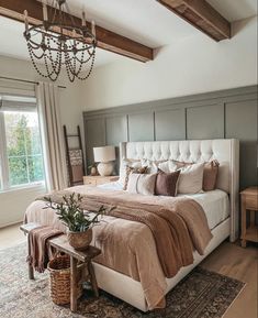 a bedroom with a large bed, chandelier and two windows in the room