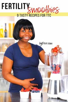 a pregnant woman standing in front of a blender filled with berries and smoothies