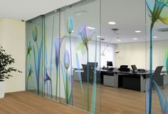 an office with glass walls and flowers painted on the wall next to a plant in a pot