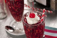 two glasses filled with liquid and topped with whipped cream, cherries and a cherry