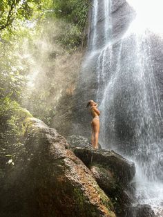 a naked woman standing in front of a waterfall