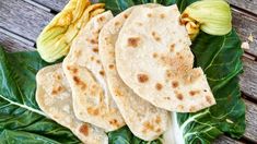 three tortillas on top of green leafy leaves next to an open flower