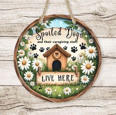 a wooden sign that says spoiled dogs and their caregiving staff is in front of some daisies