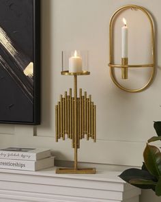 a candle holder on top of a table next to a wall mounted art piece and some books