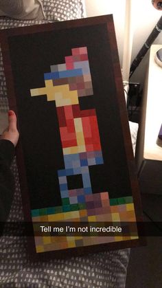 a person holding up a piece of art made out of lego blocks that says tell me i'm not incredible