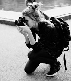 black and white photograph of a woman kneeling down with her camera in front of her