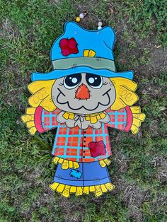 a paper cut out of a scarecrow on the ground with grass in the background