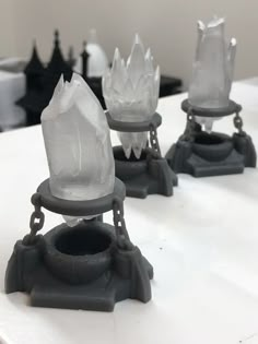 three pieces of glass sitting on top of a white table next to black and white chess pieces