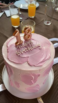 a pink birthday cake sitting on top of a table