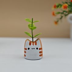 a small ceramic cat planter with a green sprout in it