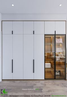 an empty bedroom with white cupboards and wood flooring on the walls, along with glass doors that open to let in light