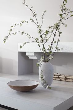 a vase with flowers in it sitting on a table next to a plate and bowl